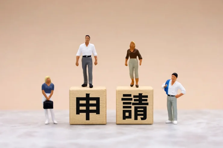 特定建設業許可申請に必要な財務諸表(貸借対照表)をチェックする担当者と積み重ねられた申請書類。